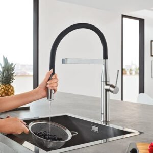 GROHE pull-out kitchen sink mixer used for washing fruits in a modern stainless-steel sink.